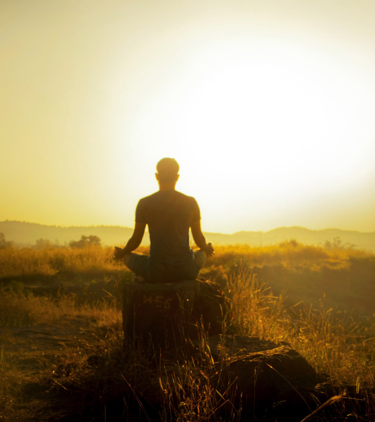 Photo of a man meditating at sunset, practicing Somatic Therapy