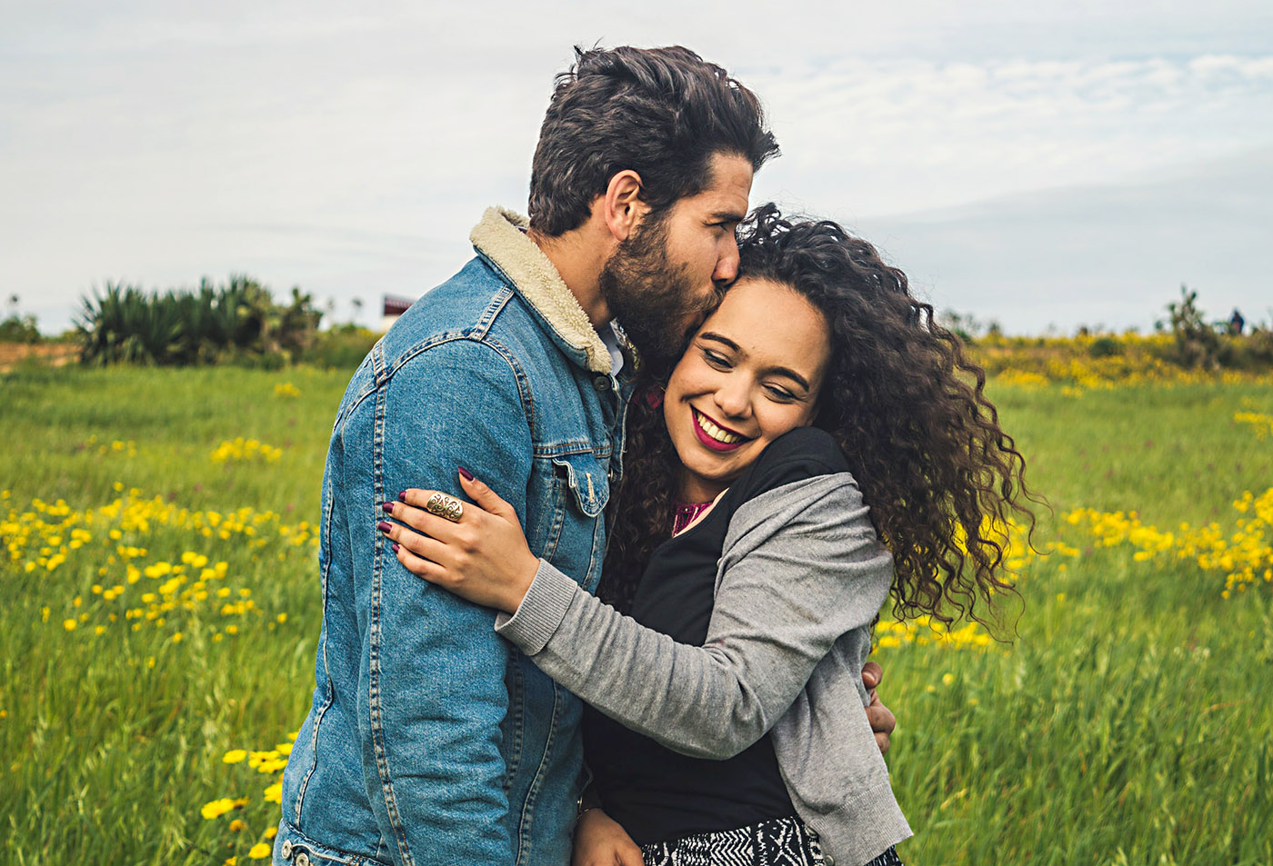 photo of a man and woman smiling and hugging in a field of flowers after couples therapy
